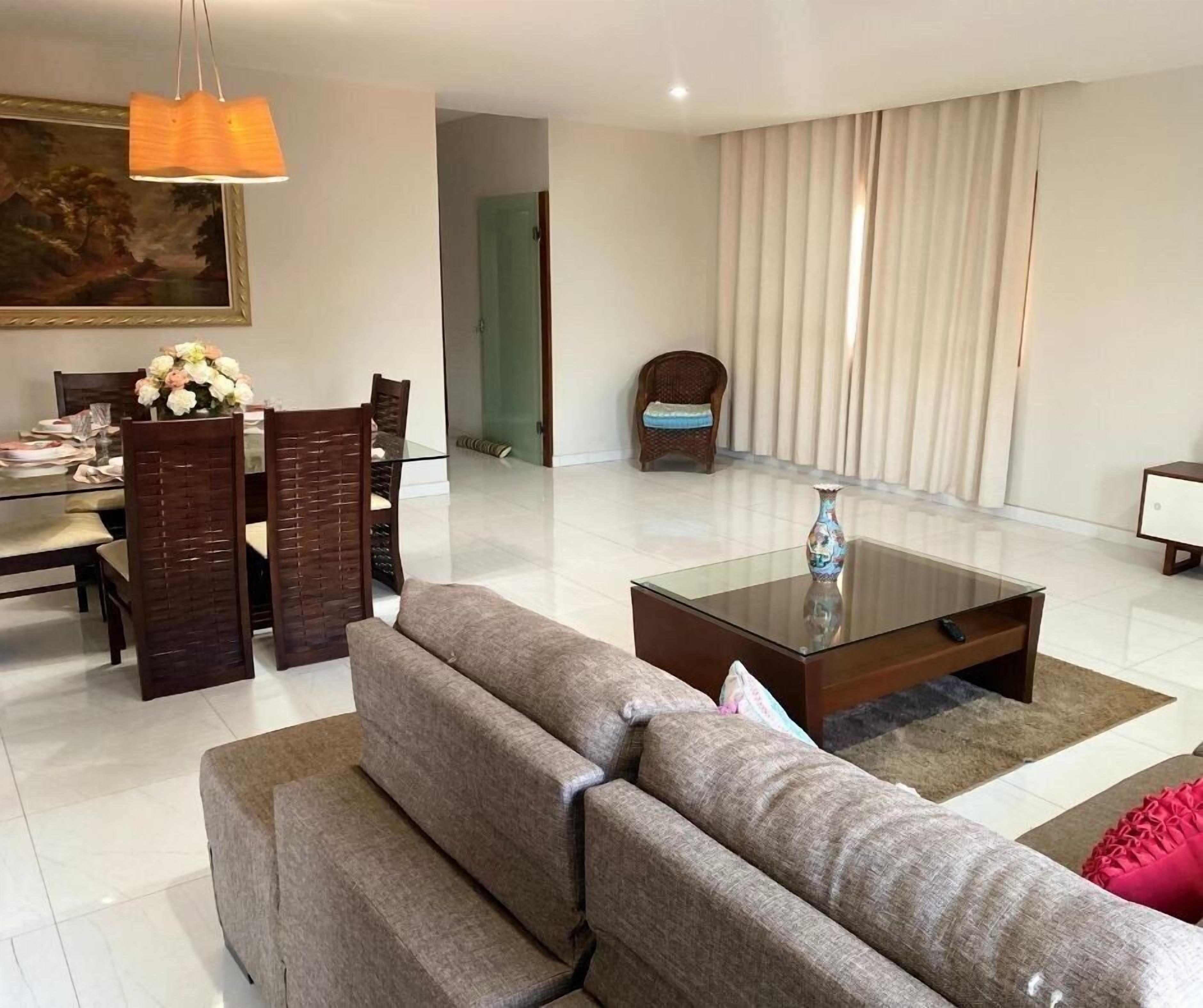 Uma sala de estar moderna com uma mesa de jantar de vidro, um sofá, uma mesa de centro e uma cadeira.