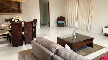 Uma sala de estar moderna com uma mesa de jantar de vidro, um sofá, uma mesa de centro e uma cadeira.