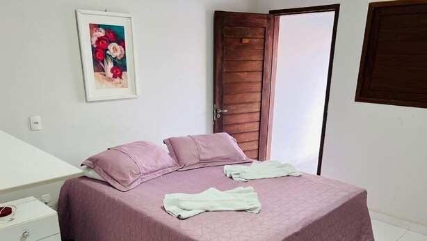 Une chambre à coucher avec un lit, une table de chevet, une porte et un tableau accroché au mur.
