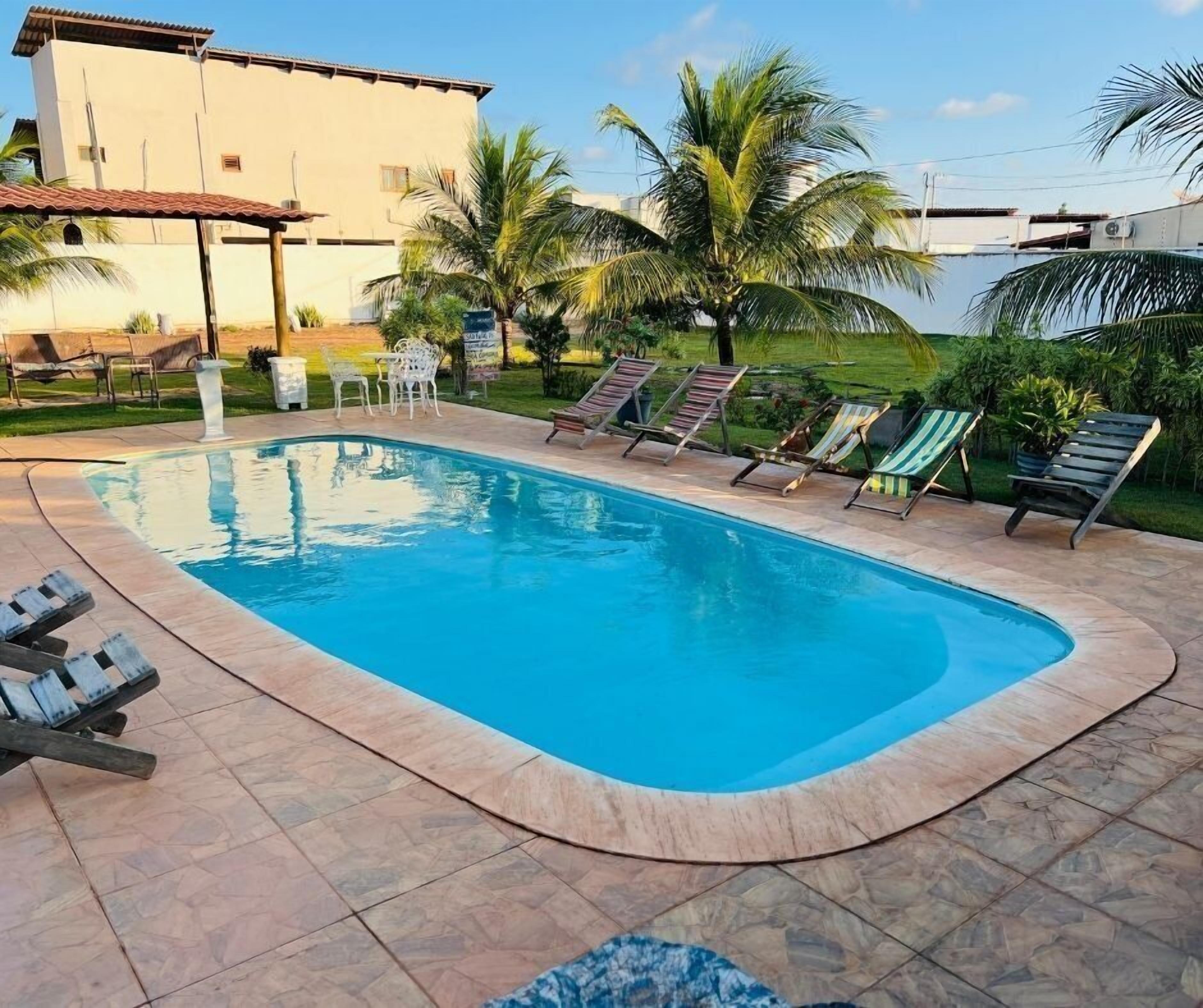 Uma piscina com espreguiçadeiras e palmeiras.