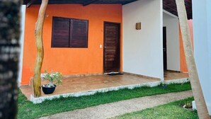 Une maison avec un toit recouvert de tuiles rouges, une porte en bois et un petit jardin.