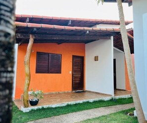 Uma casa com telhado de telhas vermelhas, porta de madeira e um pequeno jardim.