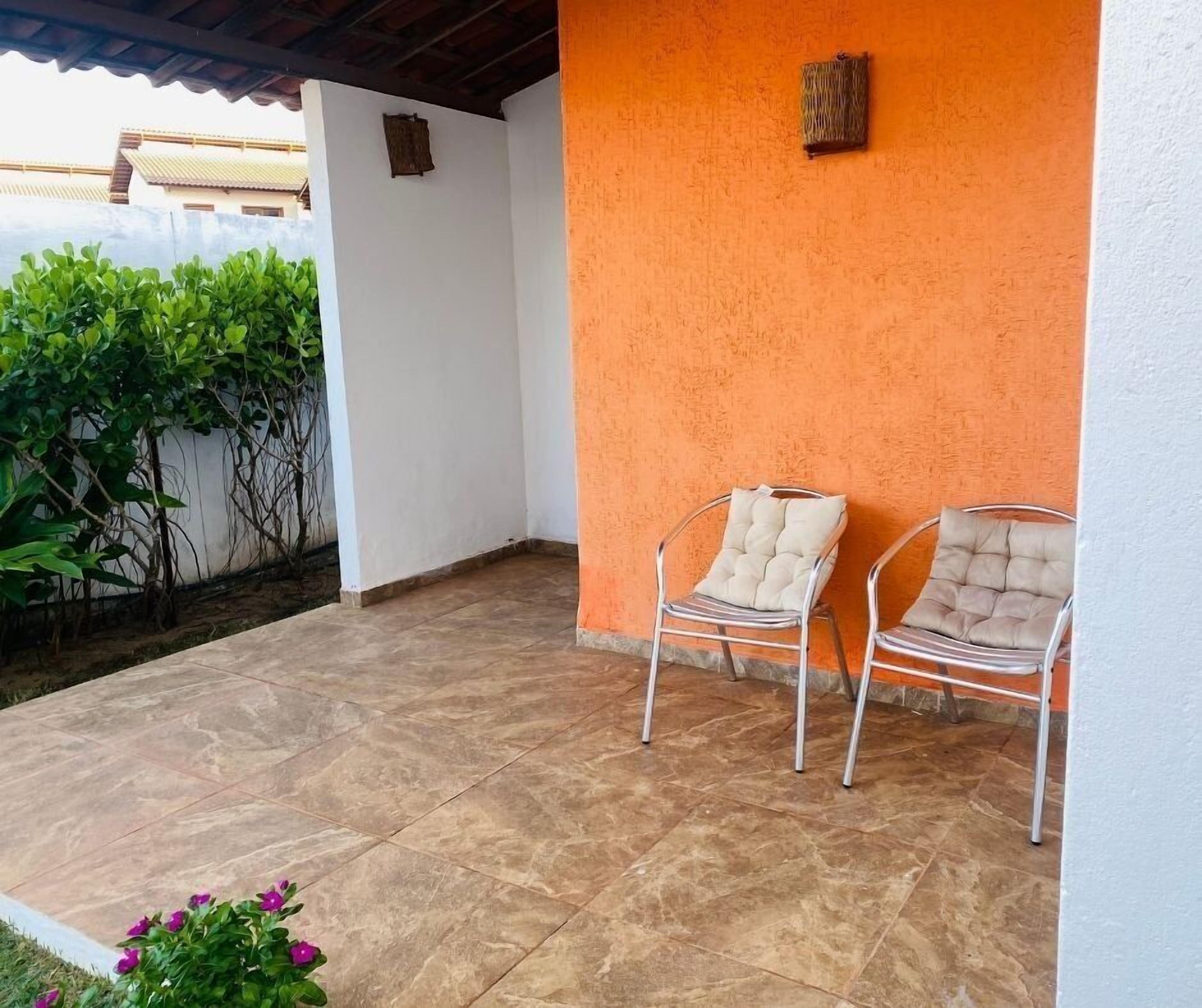Uma área externa com assentos para dois e piso de azulejos.