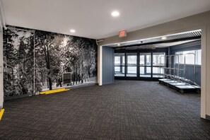 A spacious room with a patterned carpet, a mural of trees on the wall, and a view through large windows. - ML 269: Your Cozy Winter Escape | Snowy Adventures & Mountain Memories (Snowshoe)