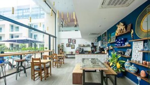 A modern cafe with wooden furniture, a glass display case, and decorative items on shelves. - Urban Studio+BigComfy Bed+EmbsyGdns, Cantonments (Accra)