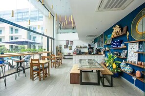 A modern cafe with wooden furniture, a glass display case, and decorative items on shelves. - Urban Studio+BigComfy Bed+EmbsyGdns, Cantonments (Accra)