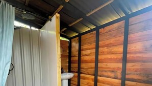 Ein Holzinnenraum mit Dusche, Waschbecken und Toilette.