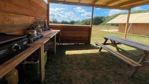 Eine rustikale Holzhütte mit Küchenbereich, einem Esstisch und einer Picknickbank.