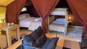 A cozy tented accommodation with a single bed, a desk, and a chair. - The Safari Tent at Pencwm Escapes (Hebron)