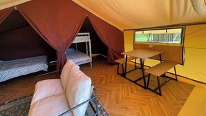 Ein Zelt mit Etagenbett, einem Tisch und einem gepolsterten Sessel.