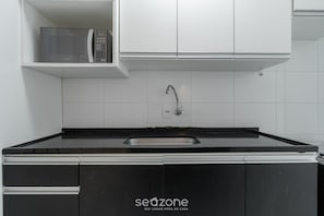 Eine Küche mit schwarzer Arbeitsplatte, einem Spülbecken und weißen Schränken.