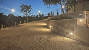 A gravel driveway leading to a stone wall with a tree on the right. - Dominò Apartment with a Stunning View of the Euganean Hills (Veneto)