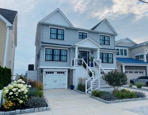 A two-story house with a front porch, a garage, and a driveway. - Spacious 5-Bedroom house on the bay with large dock and open water, sunset views (Brigantine)