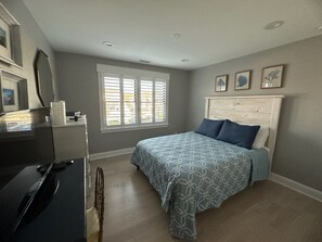 A bedroom with a bed, a desk, and a chair. - Spacious 5-Bedroom house on the bay with large dock and open water, sunset views (Brigantine)
