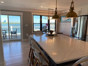 A spacious kitchen with a large island, modern appliances, and a view of the water. - Spacious 5-Bedroom house on the bay with large dock and open water, sunset views (Brigantine)
