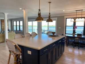 A modern kitchen with a large island, dark cabinetry, and pendant lighting. - Spacious 5-Bedroom house on the bay with large dock and open water, sunset views (Brigantine)