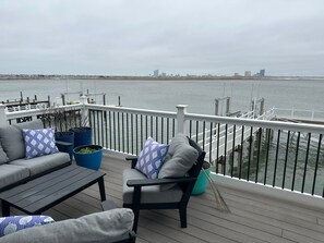 Una terrazza con mobili da esterno, un parapetto e vista sull'acqua e sullo skyline della città in lontananza.