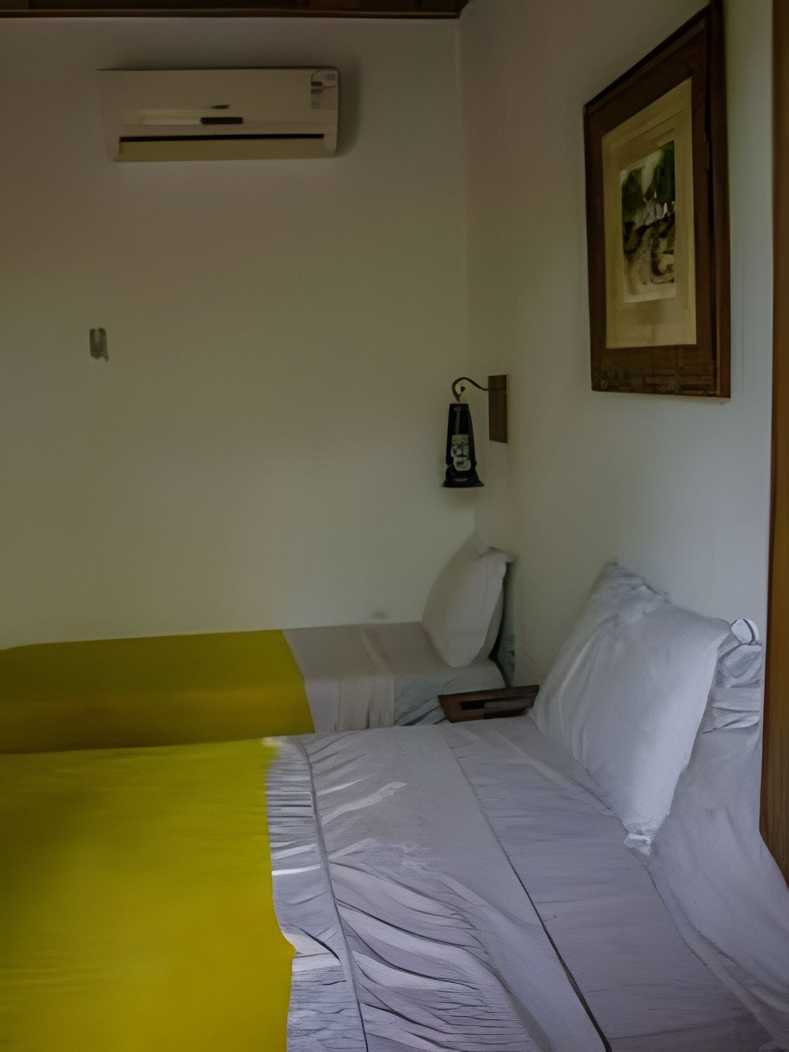A room with a bed, a nightstand, a lamp, and an air conditioning unit.