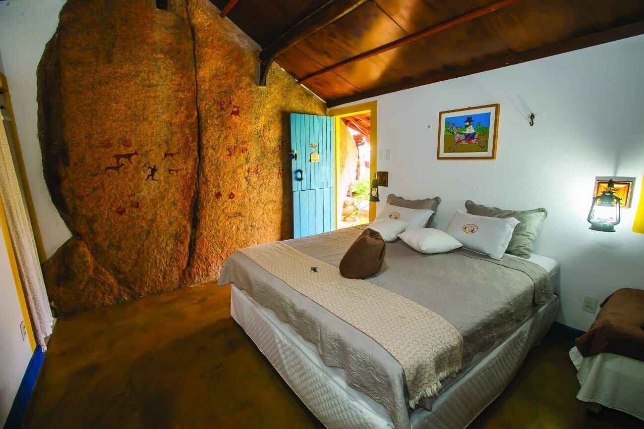 Un dormitorio con cama, una puerta azul, un cuadro y una lámpara.