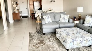 Ein modernes Wohnzimmer mit grauem Sofa, passendem Ottomanen und einem gemusterten Teppich.