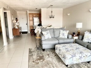 A modern living room with a grey sofa, matching ottoman, and a patterned rug. - -NEW LISTING-Waterfront Condo 2bd/2bth-Stunning Destin Harbor Views Holiday Isle (Destin)