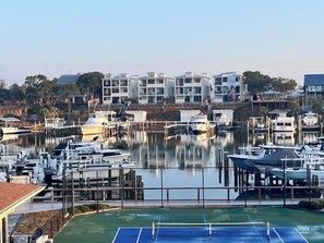 Un port de plaisance avec des bateaux amarrés, un court de tennis et des bâtiments en arrière-plan.
