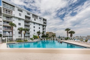 A hotel pool area with a clear sky, a multi-story building with balconies, and palm trees. - -NEW LISTING-Waterfront Condo 2bd/2bth-Stunning Destin Harbor Views Holiday Isle (Destin)