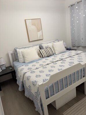 A bedroom with a white bed, a bedside table with a lamp, and a framed picture on the wall. - Gorgeous 4 Bedroom & 3 Bathroom Townhome Cottage - Blue Mountain (The Blue Mountains)