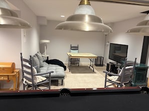 Ett modernt vardagsrum med en soffa, fåtöljer, ett bord, en tv och en öppen spis.