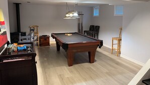 A pool table in a room with wooden flooring, a ceiling light, and two chairs. - Gorgeous 4 Bedroom & 3 Bathroom Townhome Cottage - Blue Mountain (The Blue Mountains)