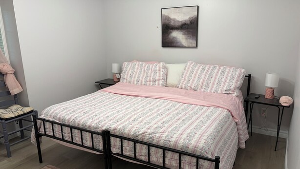 A bedroom with a bed, a nightstand, a lamp, and a painting on the wall. - Gorgeous 4 Bedroom & 3 Bathroom Townhome Cottage - Blue Mountain (The Blue Mountains)
