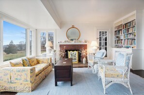 Ein Wohnzimmer mit Kamin, einer Couch, einem Sessel und einem Bücherregal.