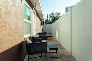 An outdoor patio area with wicker furniture and a white fence.