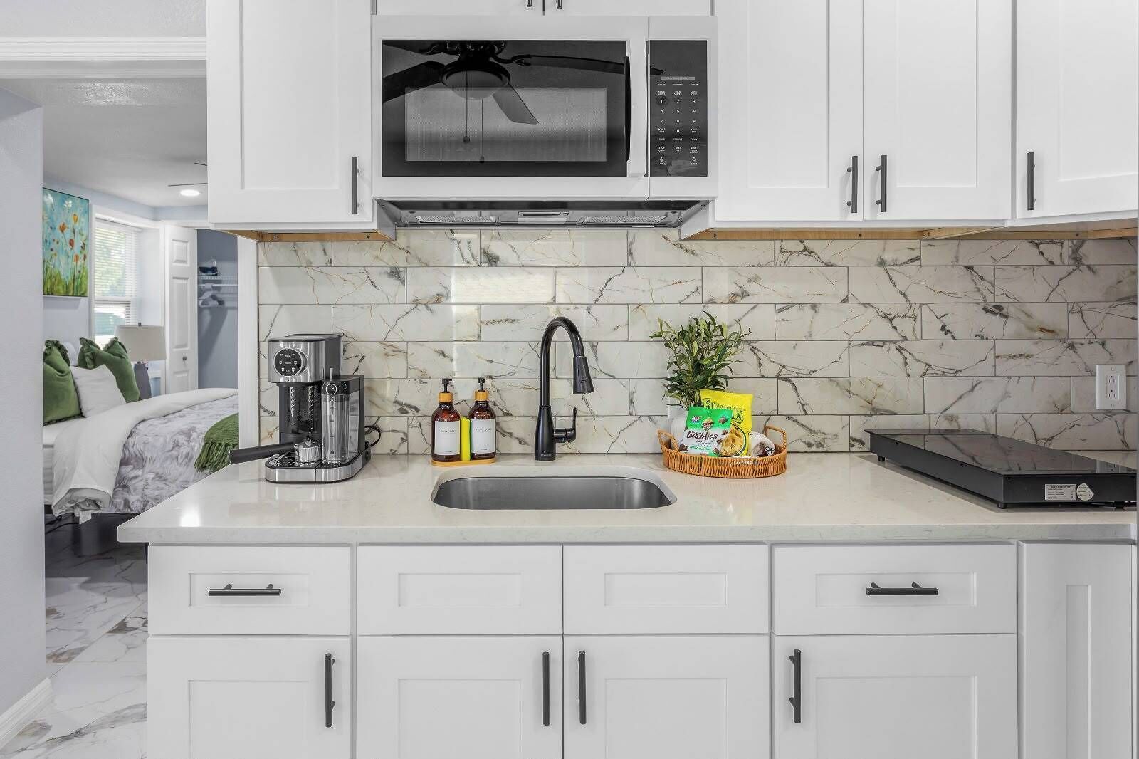A modern kitchen with a built-in microwave, a coffee maker, and a sink.