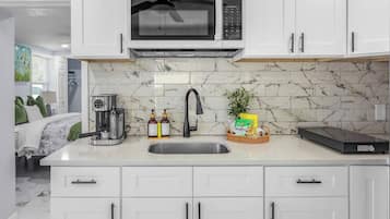 A modern kitchen with a built-in microwave, a coffee maker, and a sink.