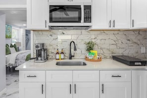 A modern kitchen with a built-in microwave, a coffee maker, and a sink.