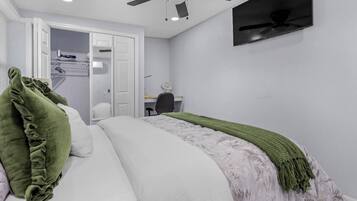 A bedroom with a bed, a desk, a chair, a ceiling fan, and a wardrobe.