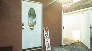 A white door with a window, a doormat, and a sign with a red bow.