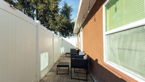 A patio with outdoor furniture and a white fence.