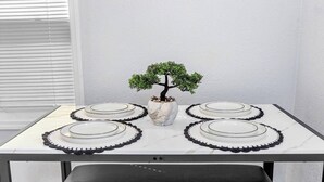 A table set with plates and a vase with a bonsai tree.