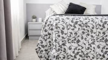 Quarto com cama, mesa de cabeceira e uma pequena planta.