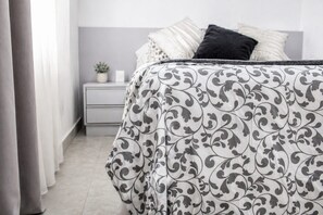 Een slaapkamer met een bed, nachtkastje en een kleine plant.