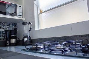 A modern kitchen with a gas stove, a blender, and a coffee maker. - 4let BH Del Rey (Belo Horizonte)