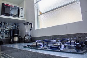 Een keuken met een gasfornuis, een koffiezetapparaat en een magnetron.