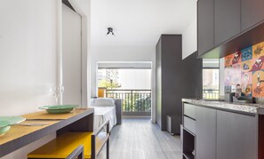 A narrow kitchen with a wooden countertop, a dining area with a table and chairs, and a view of the outside balcony. - Studio in Condominium w/ Pool in Sao Paulo Thk0202 (São Paulo)