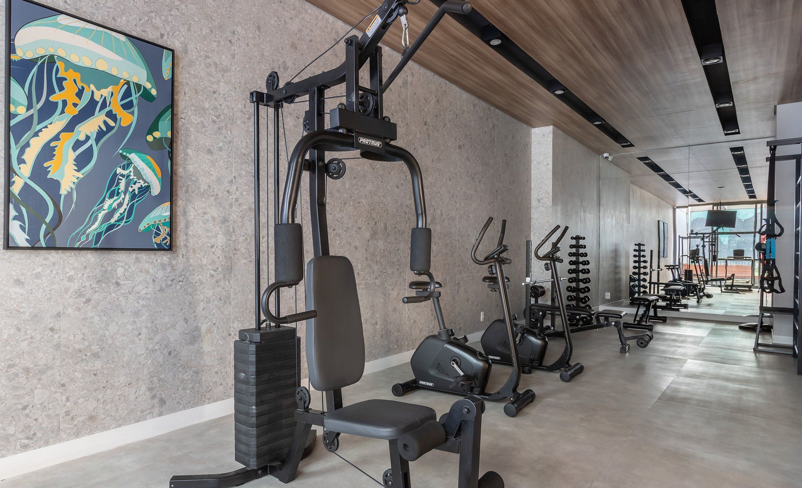 Ein Fitnessraum mit Trainingsgeräten, einer Bank und einem großen abstrakten Gemälde an der Wand.