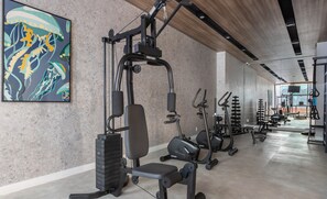 A gym with exercise equipment, a bench, and a large abstract painting on the wall. - Studio in Condominium w/ Pool in Sao Paulo Thk0202 (São Paulo)