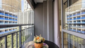 A balcony with a potted plant, a view of a building with blue scaffolding, and a metal railing. - Complete Studio 350m From the Metro Thk0502 (São Paulo)