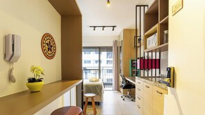 A compact hotel room with a kitchenette, a bed with a view, a small stool, and a potted plant. - Complete Studio 350m From the Metro Thk0502 (São Paulo)