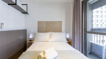 Hotelkamer met een bed, twee nachtkastjes, een hoofdbord en een raam met uitzicht op gebouwen.